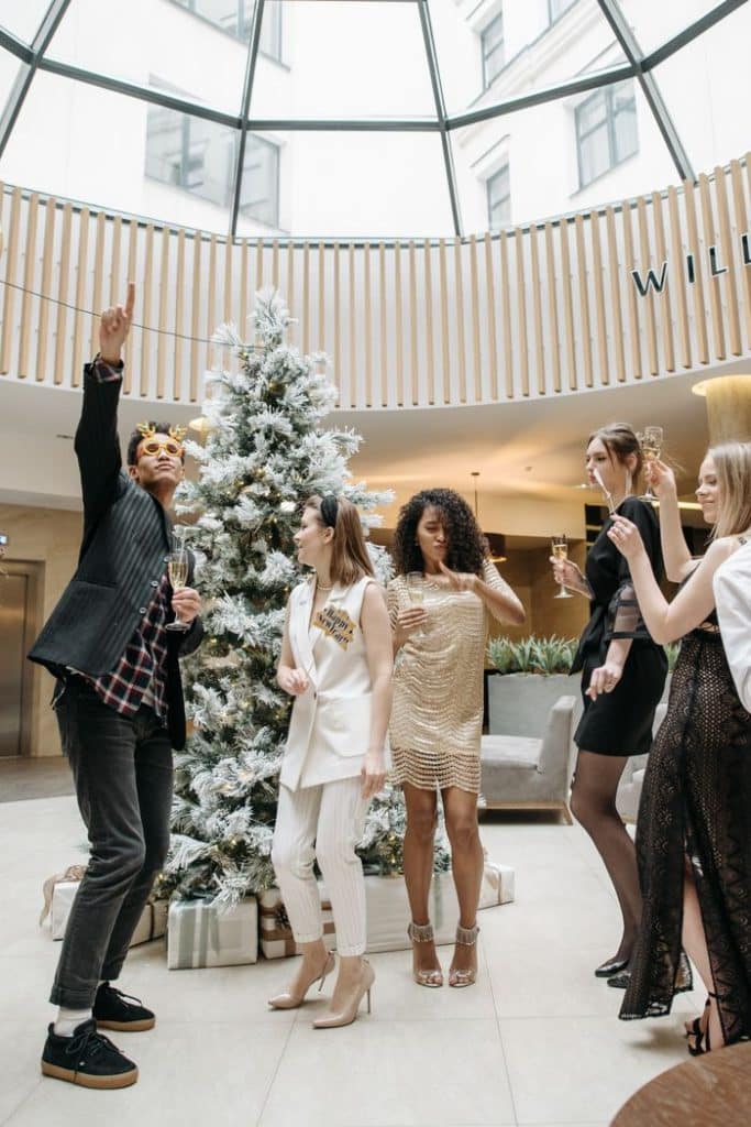 pexels-photo-6405798-6405798 Group of diverse adults celebrating a festive Christmas party indoors with a decorated Christmas tree.