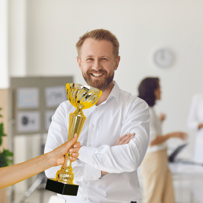 A man in an office with a trophy being presented to him