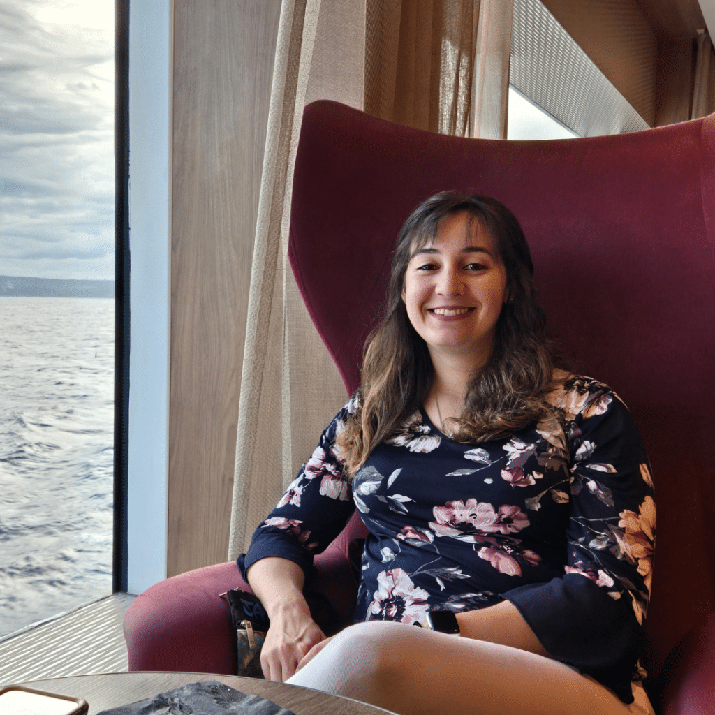 Marcella Kuchar a travel advisor for Best Adventure Spots in Fort Myers sitting in an elegant red chair wearing a floral dress on a cruise ship